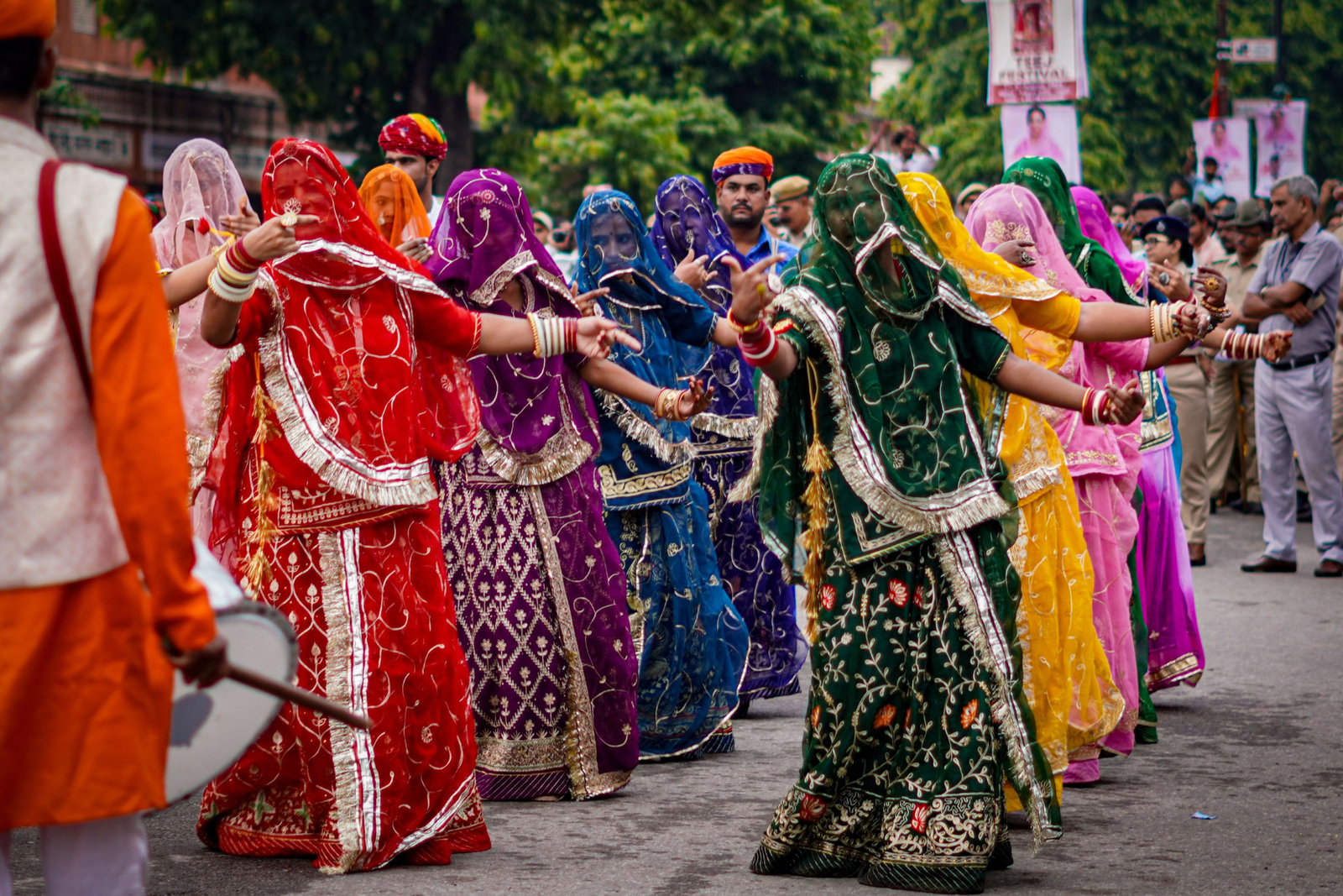 A group of women owns the centre of the crowd while the dhol keeps its rhythm. The wet ground gives it away. A shower has just passed through, which is half the reason the streets feel this alive.