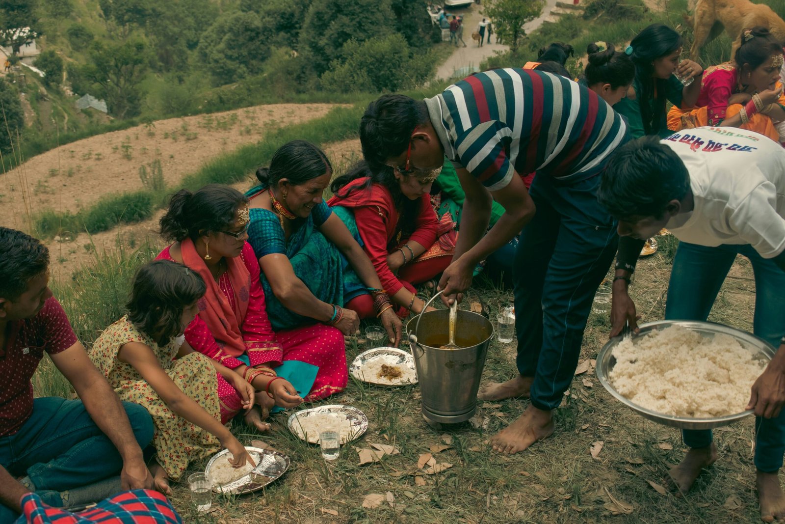 A community meal served on the ground with dal ladled straight from the pot and rice by the plateful